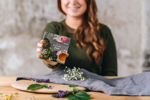 Jemand hält eine Packung Ja! Natürlich Bio-Kräutertee.