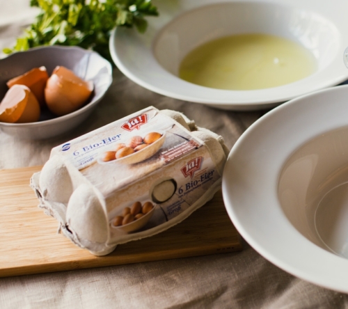 Eine Schüssel mit Eiklar, daneben ein Karton Ja! Natürlich Bio-Eier.