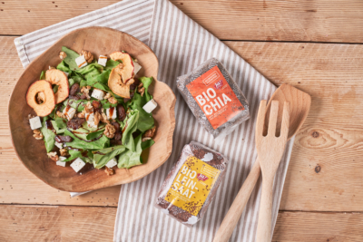 Eine Schüssel mit Salat, Apfel und Feta, daneben zwei Packungen Ja! Natürlich Bio-Chia-Samen und Leinsaat.