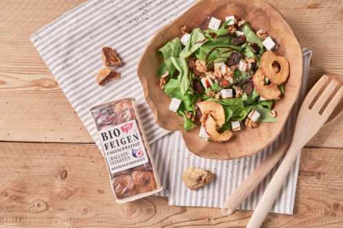 Schüssel mit Salat, Feta, getrockneten Apfelringen und Ja! Natürlich Bio-Feigen.