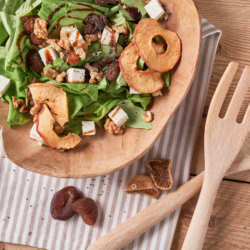 Bio-Frühlingssalat mit Schafskäse, Trockenfrüchten und Apfelchips in einer Schüssel.