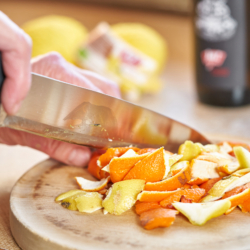 Jemand schneidet die Schalen von Ja! Natürlich Bio-Zitronen und Orangen.