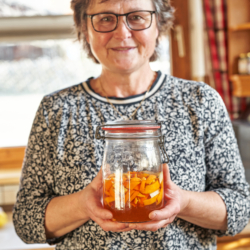 Jemand hält ein Glas mit eingelegten Orangenschalen.