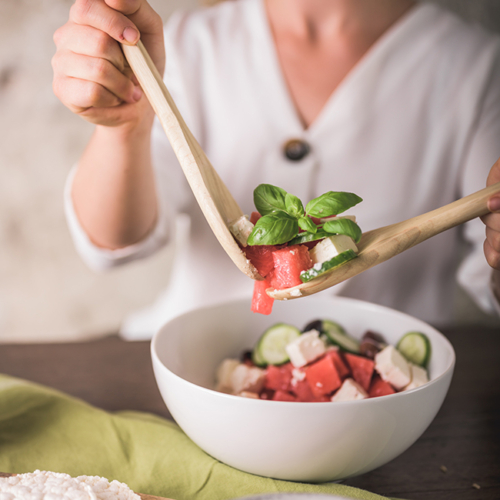 Jemand nimmt sich einen gemischten Bio-Salat aus der Schale.