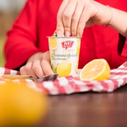 Jemand öffnet einen Becher Ja! Natürlich Bio-Sommerfrisch Zitrone.