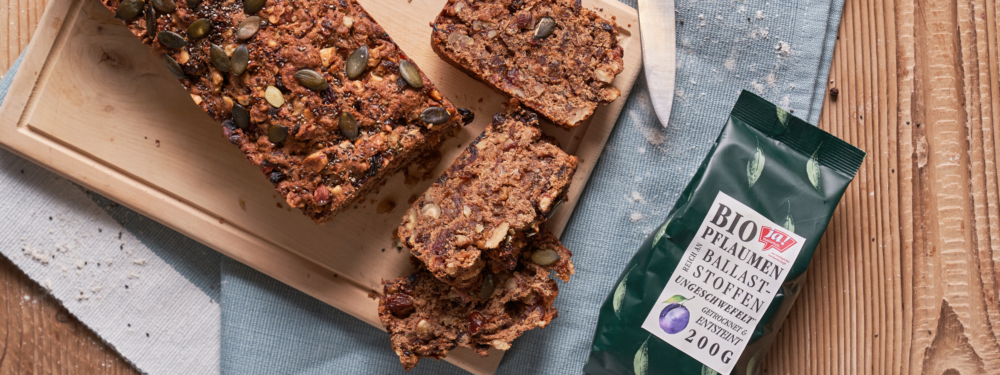 Veganer Früchtestollen aufgeschnitten und eine Packung Ja! Natürlich Bio-Pflaumen daneben.