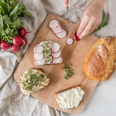Auf einem Holzbrett liegen drei aufgeschnittene Brote, jeweils mit Aufstrich.