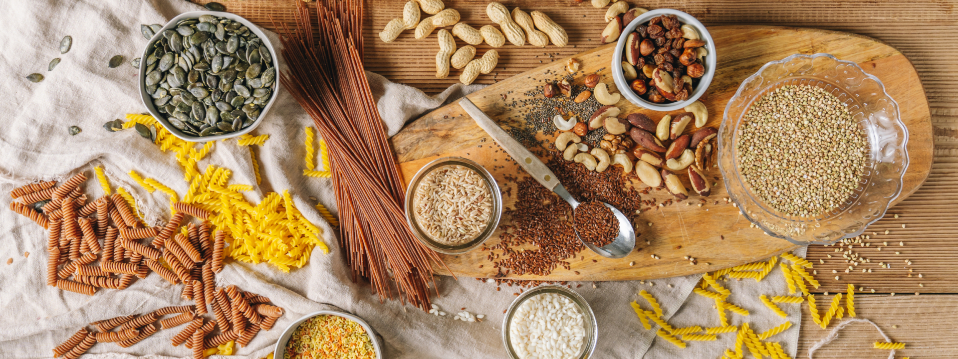 Bio-Nudeln und verschiedene Körner auf einem Schneidebrett präsentiert.