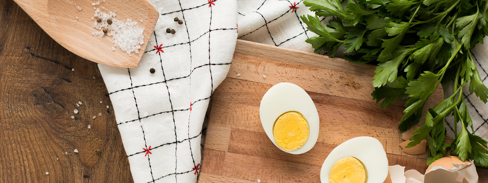 Gekochte Bio-Eier auf einem Schneidebrett mit einem Kochlöffel und Koriander.