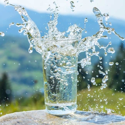 Ein Glas Wasser, aus dem Wasser spritzt.