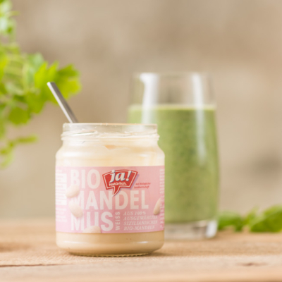 Ein Glas Ja! Natürlich Bio-Mandelmus und ein Glas grüner Smoothie.