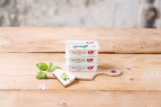 Verschiedene Sorten Ja! Natürlich Bio-Frischkäse auf einem Holzbrett.