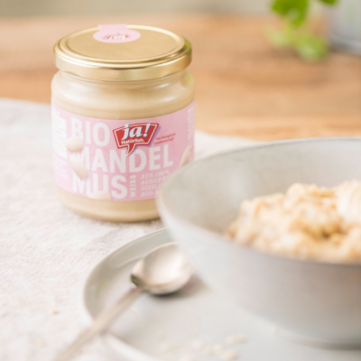 Ein Glas Ja! Natürlich Bio-Mandelmus und eine Schüssel mit Porridge.