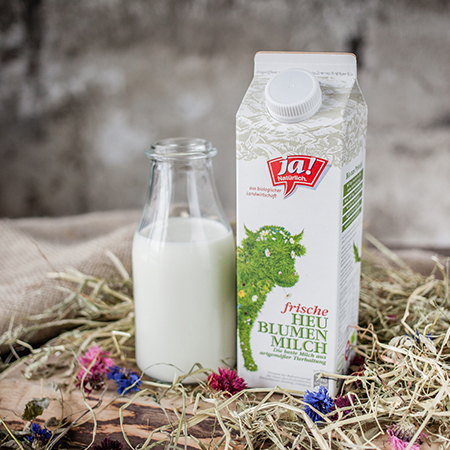 Ein Karton Ja! Natürlich Bio-Vollmilch neben einem Glas mit Milch.