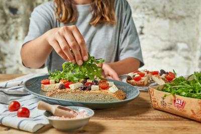 Jemand gibt Ja! Natürlich Bio-Ruccola auf Focaccia.