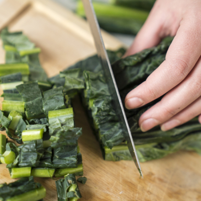 Jemand schneidet Bio-Schwarzkohl.