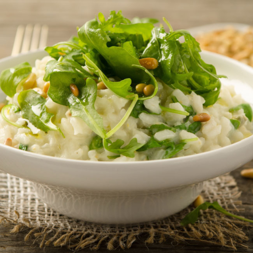 Eine Schale mit Bio-Rucolarisotto mit Pinienkernen und Bergkäse.