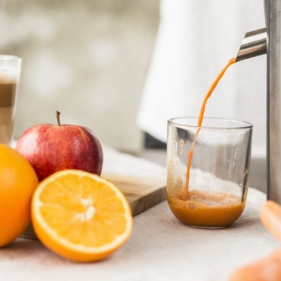 Eine Obstpresse mit Bio-Äpfeln und Orangen.