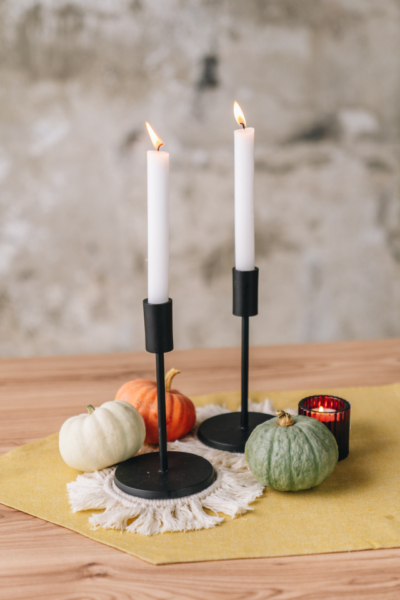Dekorierte Kerzenständer mit Kürbissen und Teelichtern.