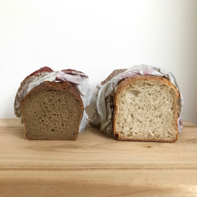 Zwei Laibe Bio-Brot auf einem Schneidebrett.