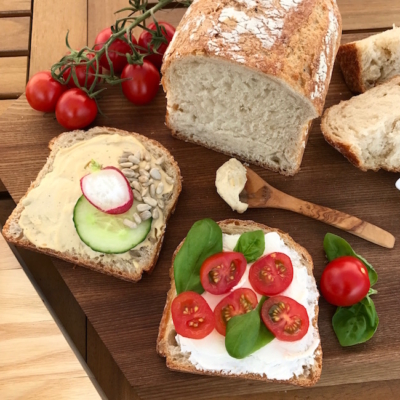 Zwei Scheiben rustikales Bio-Weißbrot mit Aufstrichen und Gemüse.