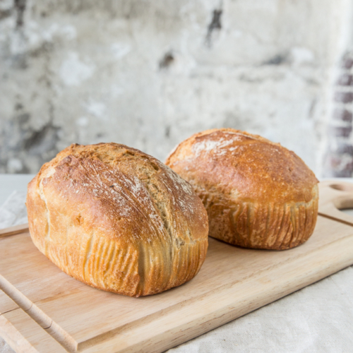 Zwei Laibe Bio-Brot auf einem Schneidebrett.