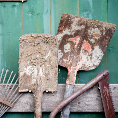 Gartenwerkzeug an eine Wand gelehnt.