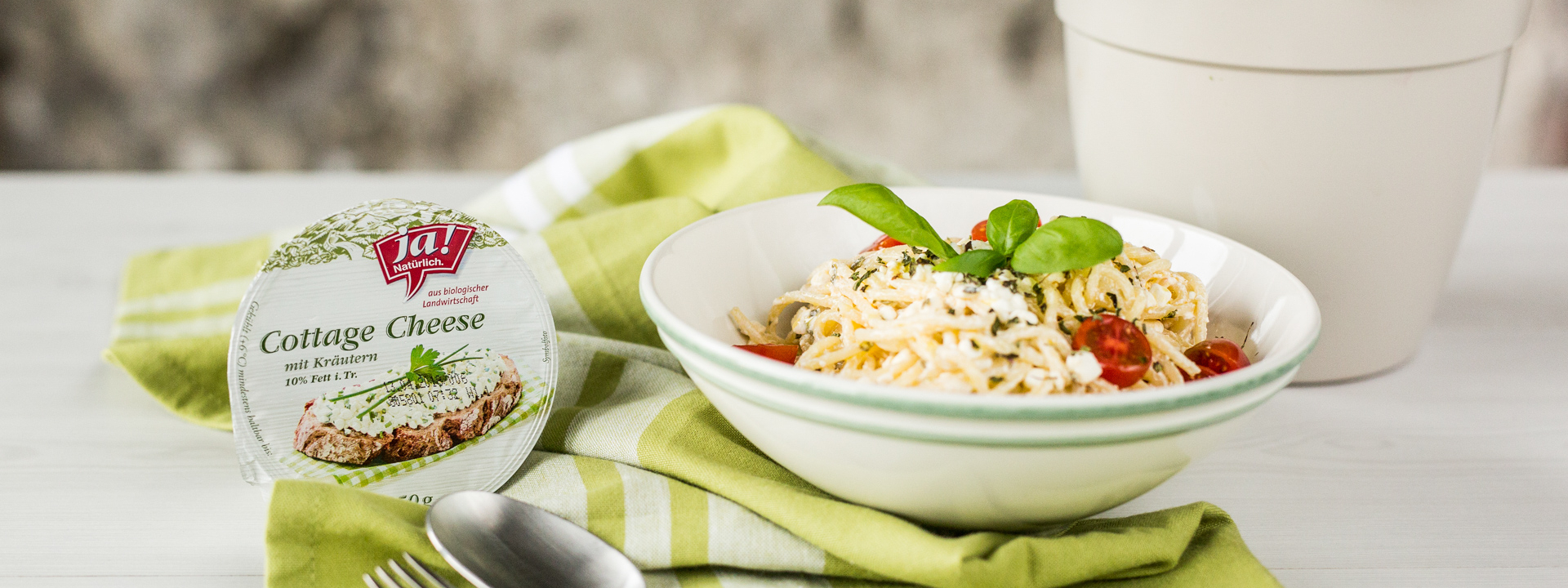 Eine Packung Ja! Natürlich Bio-Cottage Cheese mit Kräutern und Pasta in einer Schüssel.