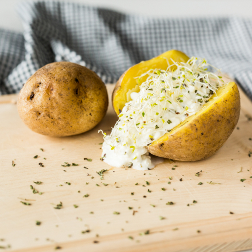 Ein Brett mit Bio-Offenkartoffeln mit Cottage Cheese und Kräutern.