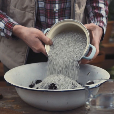 Jemand schüttet Bio-Katzenstreu in eine Schüssel.