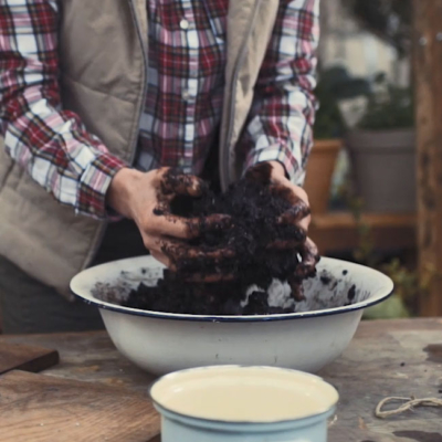 Jemand gibt Erde in eine Schüssel.