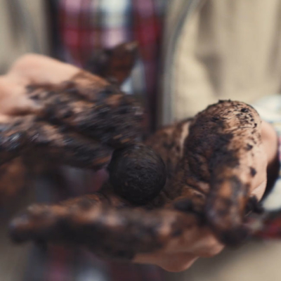 Jemand rollt die Erde mit Samen in eine Kugel.