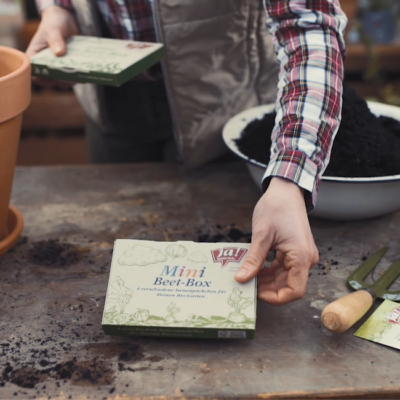 Jemand legt eine Ja! Natürlich Mini Beet-Box auf einen Tisch.