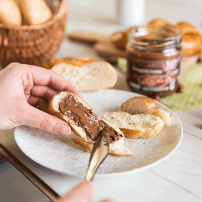 Jemand bestreicht ein Stück Striezel mit Ja! Natürlich Bio-Nougatcreme.