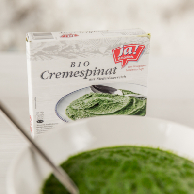 Eine Packung Ja! Natürlich Bio-Cremespinat mit einer Schüssel Cremespinat.