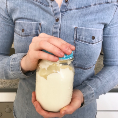 Jemand hält ein Marmeladenglas mit Schlagsahne.