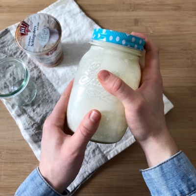 Jemand schüttelt den Schlagobers in einem Marmeladenglas.