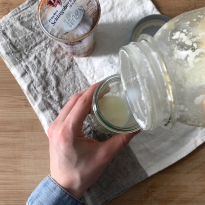 Jemand leert die Buttermilch in ein Glas.