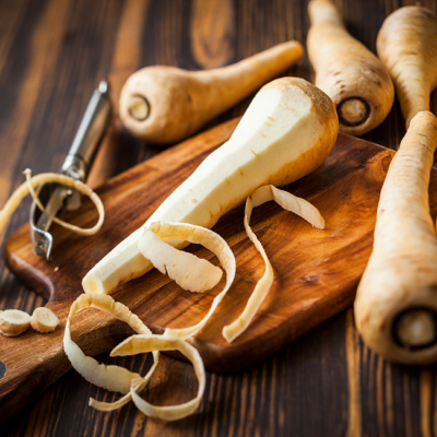 Geschälte Bio-Pastinake auf einem Holzbrett.