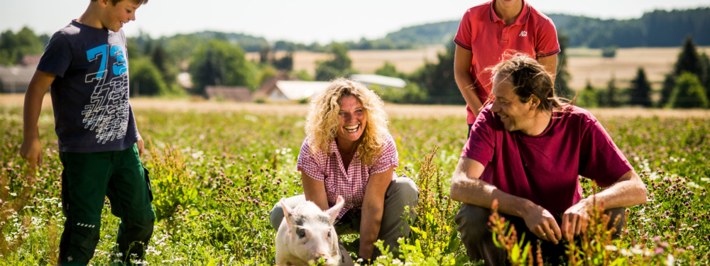 Mehrere Personen hocken neben einem Ferkel.