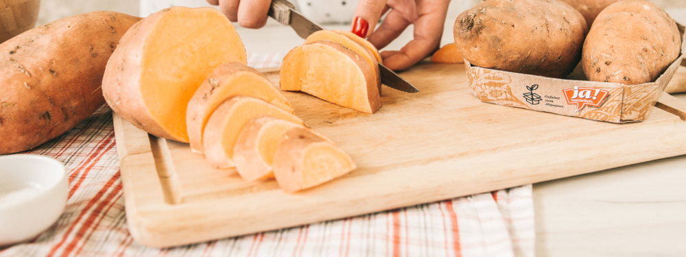 Jemand schneidet eine Ja! Natürlich Bio-Süßkartoffel.