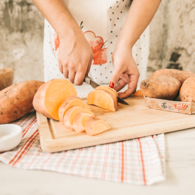Jemand schneidet eine Ja! Natürlich Bio-Süßkartoffel.