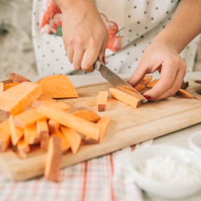 Jemand schneidet eine Bio-Süßkartoffel.