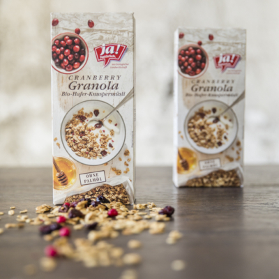 2 Packungen Ja! Natürlich Bio-Granola Cranberry auf einem Tisch.