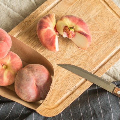 Aufgeschnittener Bio-Plattpfirsich mit einem Messer.