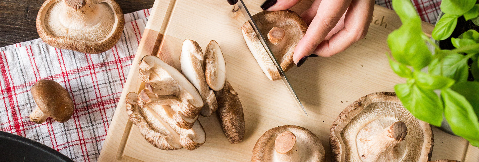 Jemand schneidet Bio-Shiitake-Pilze.