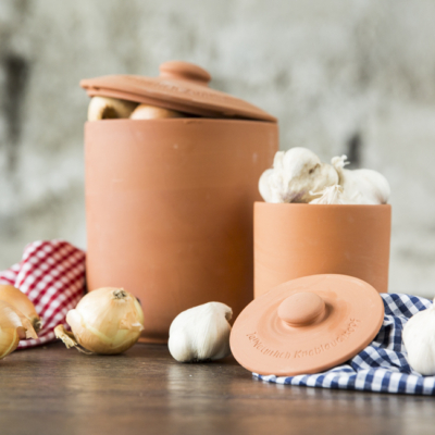 Bio-Zwiebeln und Knoblauchknollen in Tontöpfen.