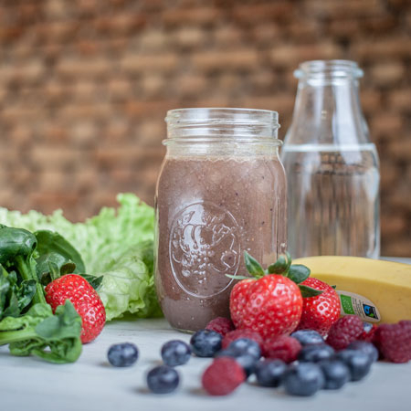 Bio-Smoothie umgeben von Früchten.