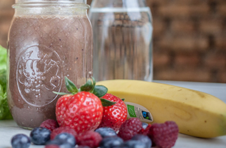 Bio-Smoothie umgeben von Früchten.