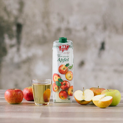 Eine Packung Ja! Natürlich Bio-Apfelsaft, ein Glas voll mit Saft und Äpfel.